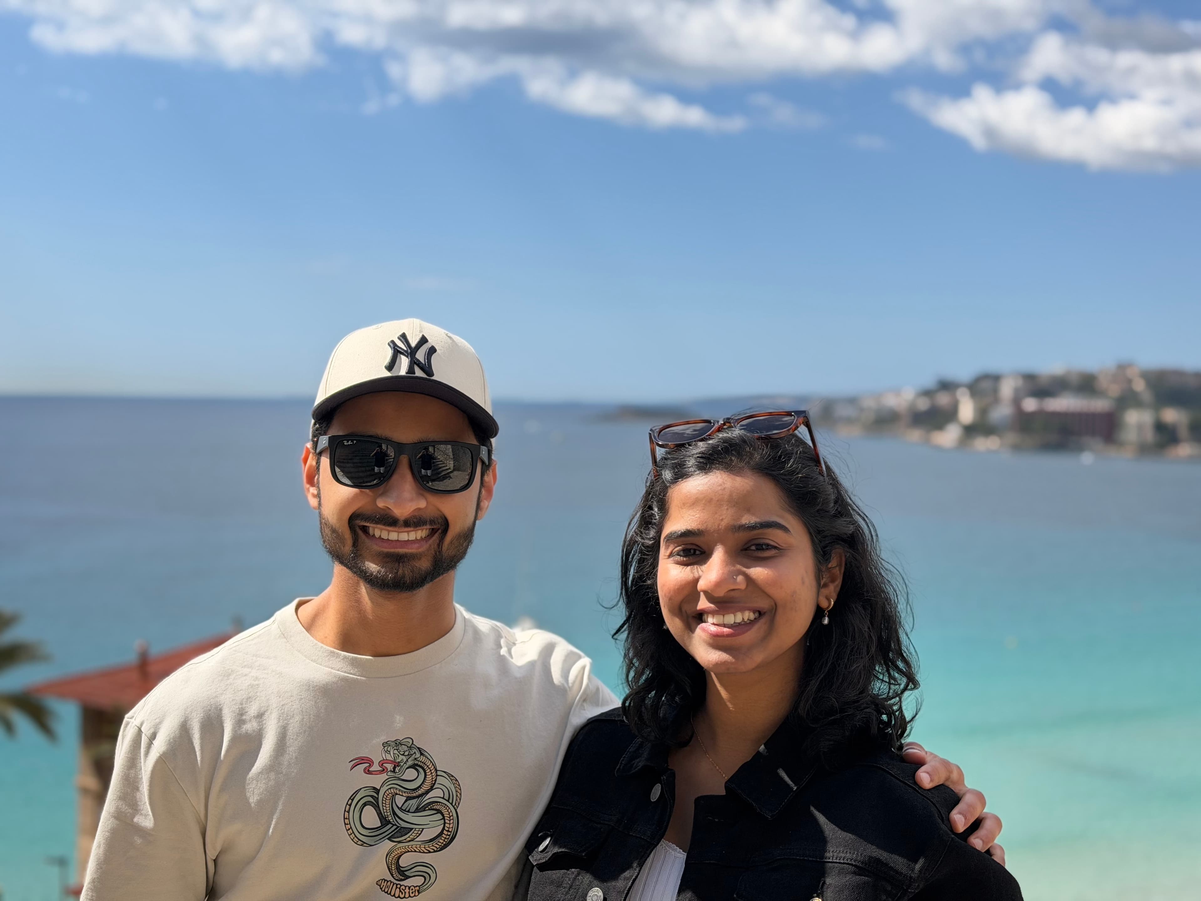 Heramb and Anuja smiling together by the sea